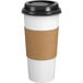 A white paper hot cup with a black lid and brown sleeve.