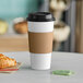A Choice white paper hot cup with a brown lid and a croissant on a table.
