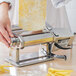 A person using a Weston Roma electric pasta machine to make dough for pasta on a counter.