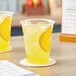 Two Choice translucent plastic cups of lemonade on a table.