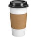 A white paper coffee cup with a brown band around it and a black lid.