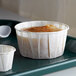 A white Genpak paper souffle cup filled with food on a tray.
