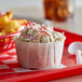 A red tray with a Genpak paper souffle cup of fries and a bowl of coleslaw.