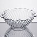 A clear glass GET tulip bowl with a curved edge on a table.