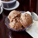 A clear tulip bowl filled with a scoop of chocolate ice cream.