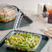 Two Dart ClearSeal plastic containers with salad in one and a sandwich in the other on a table.