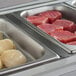 A white hotel buffet tray with raw meat and scallops divided with an Avantco divider bar.