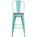 A mint green metal bar stool with a wood seat and vertical slat back.