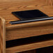 A black rectangular tablet sits on a medium oak wooden Oklahoma Sound host stand.