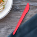 A coral Eco-Products compostable plastic knife on a table.