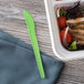 A green plastic container with a salad and a white container with a green Eco-Products compostable plastic knife.
