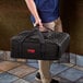 A man carrying a Cambro black insulated pizza delivery bag.