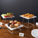 An Acopa stainless steel display stand set with trays of muffins on a table.