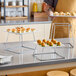 A set of three square stainless steel metal display stands of varying heights, used for presenting food items.