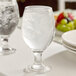 A clear 14 oz. glass goblet filled with ice water.