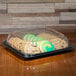 A clear plastic Sabert catering tray with cookies and green icing inside.