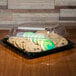 A Sabert plastic tray with cookies and a high dome lid on a table.