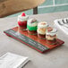 An Acopa Write-On Flight Tray with desserts in jars on a wood table.