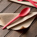 A red Eco-Products Plantware compostable plastic spoon on a napkin.