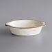 An Acopa Keystone stoneware oval casserole dish in white with brown trim.