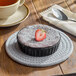 A black porcelain souffle or creme brulee dish filled with a chocolate dessert, topped with powdered sugar and a halved strawberry.