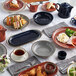 A table with Acopa Keystone vanilla bean stoneware souffle dishes filled with food.