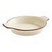 A round, cream-colored porcelain casserole dish with two side handles and a brown rim.