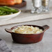 A bowl of mashed potatoes and green beans in an Acopa chestnut stoneware mini casserole dish.