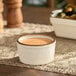 A small vanilla bean stoneware ramekin filled with sauce.