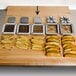 A metal square with a grid of holes cutting board with french fries and potato wedges using the Choice Prep 1/2" French Fry Cutter.