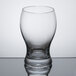 A Stolzle clear tumbler with a small amount of liquid in it.