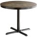 A Lancaster Table & Seating round wooden table with a cast iron base.