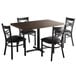 A Lancaster Table & Seating butcher block dining table with 4 black chairs.