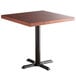 A Lancaster Table & Seating square wood table with mahogany finish and cast iron base.