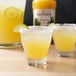 A group of glasses of yellow Monin margaritas with lime slices on the rim.