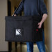 A man carrying a large black bag with the Cambro logo.