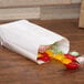 A Duro white paper bag filled with candy on a table.
