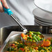 A person using a Vollrath teal spoodle to serve vegetables from a metal pan.