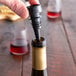 A person using a Franmara Twist-Pour wine stopper to pour wine into a bottle.