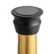A close-up of a Franmara black and gold metal wine bottle stopper.