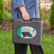 A person holding a black case with a Choice Green portable gas stove inside.