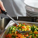 A person using a Vollrath black perforated portion spoon to serve vegetables.