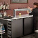 A woman pouring beer from a Beverage-Air 12 tap kegerator on a bar counter.