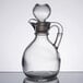 A clear glass cruet with a handle and a stopper.