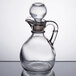 A clear glass cruet with a handle and stopper.