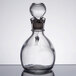 A close-up of a Libbey clear glass cruet with a metal stopper.