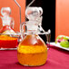 A Libbey cruet filled with orange liquid on a table.