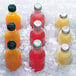 A group of six bottles of different colored drinks in ice from a Manitowoc air cooled flake ice machine.