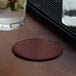 A hand placing a H. Risch, Inc. customizable coaster under a glass of water on a table.