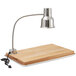 An Avantco stainless steel carving station lamp on a wooden cutting board.
